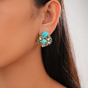 Close-up of vintage geometric earrings with turquoise stones and crystals worn by a model