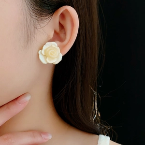 Gros plan sur des boucles d'oreilles roses en résine blanc cassé portées par un mannequin