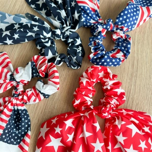 Detailed view of four American flag patriotic bow scrunchies on a wooden surface