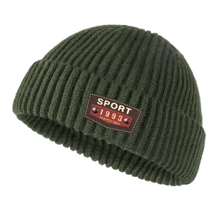 Detailed knit texture and brown faux leather patch on a dark green winter beanie hat