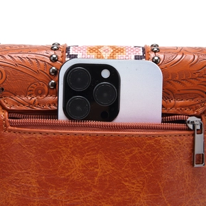 Macro view of bohemian carved leather crossbody bag with vintage rivets and rear zipper pocket