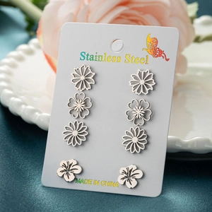Detailed view of four pairs of floral stainless steel stud earrings on a card