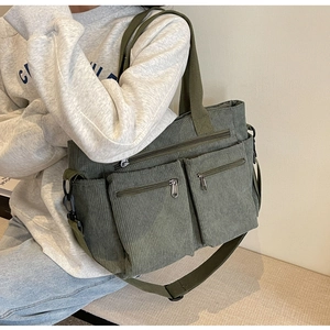 Deep green corduroy tote bag showing multiple pockets and adjustable shoulder strap detail
