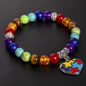 Close-up of natural stone chakra beads bracelet with colorful puzzle heart charm