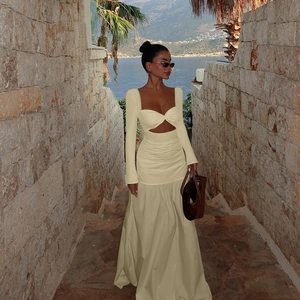 Detail of light beige long sleeve dress featuring waist cutouts and pleated empire waist