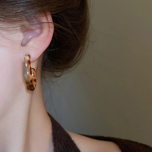 Close-up of vintage resin C-hoop earrings with leopard print and amber tortoiseshell pattern