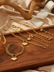 Detailed close-up of golden heart bracelets with mixed link chains on luxury silk background