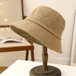 Khaki wide brim bucket hat with textured fabric displayed on a wooden stand