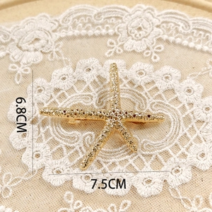 Detail shot of golden starfish hair accessory with 7.5cm width and 6.8cm height dimensions