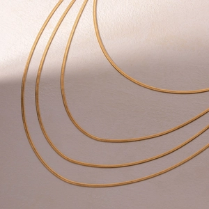 Detailed close-up showing four layered 5mm golden snake flat blade chains in stainless steel