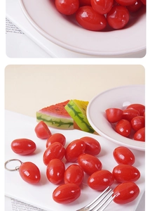 Close-up of realistic red tomato keychain charm on white tray with silver metal ring