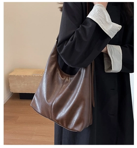 Brown soft leather hobo bag side view on model wearing a black coat for commute