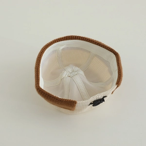 Detail view of corduroy brimless docker hat showing adjustable buckle and knit trim