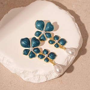 Vintage dark blue enamel flower earrings with white teardrop pearls on stone background