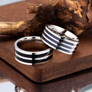 Macro detail of silver and black titanium rings with enamel stripes on wooden base