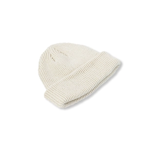 Detailed close-up of cream knit beanie featuring thick spiral texture and wide folded cuff
