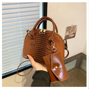 Detail of brown crocodile pattern shell bag featuring metal clasps and matching mini pouch