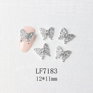 Macro shot of 3D silver butterfly nail charms with micro-pave crystals on pink nails