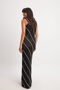 Side view of a model in a crochet maxi dress with elegant black and white diagonal stripes