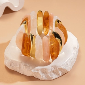 Detailed close-up of acrylic resin beads and gold metal links on an elastic bracelet