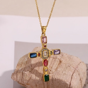 Collier croix en acier plaqué or 18K avec pierres précieuses colorées sur fond de pierre