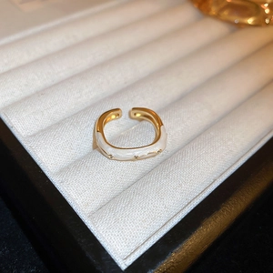 Detailed close-up of a gold-plated dragon ring with white enamel finish on a velvet tray