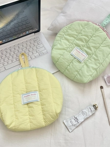 Quilted shell-shaped cosmetic bags in yellow and mint green with portable handles