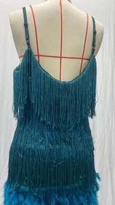 Detailansicht des pfauenblauen Paillettenkleides mit Fransen und Federn am Saum