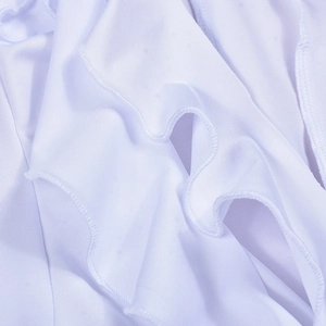 Close-up of white ruffled hollow-out dress showing detailed stitching and fabric layers