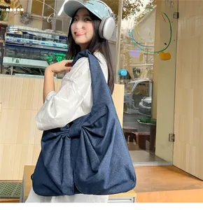 Détail du grand sac à épaule en denim bleu avec un design élégant à nœud papillon