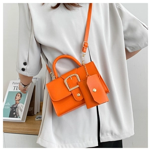 Detail of orange satchel with gold buckle and matching coin purse on crossbody strap