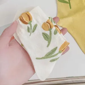 Cream cotton mid-tube socks featuring yellow tulip embroidery and soft knit texture