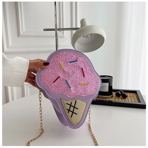 Detail of purple ice cream crossbody bag with pink glitter and gold chain on white table