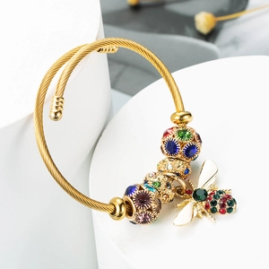 Detail of a gold bee pendant with colorful rhinestones on a twisted cable bracelet