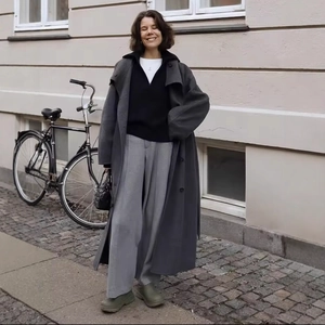 Women's long grey coat with double buttons and wide leg trousers in a city street view