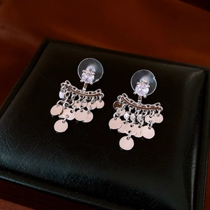 Macro detail of silver tassel earrings with round zircon studs and hanging metallic discs