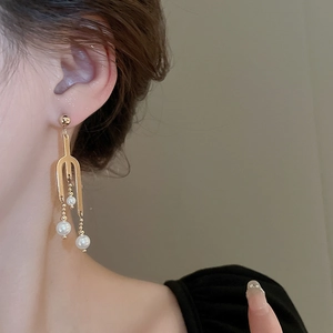 Elegant gold-tone long pearl tassel earrings shown on a model with minimalist design