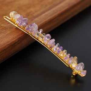 Golden hair clip with purple and yellow natural crystal stones on a wooden background