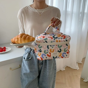 Quilted floral makeup bag with colorful wavy patterns and top handle in cozy kitchen setting
