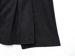 Close-up of black loose shirt fabric showing woven texture and pleated stitching details