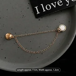 Close-up of golden magnetic chain clip for T-shirt length adjustment and styling accessory