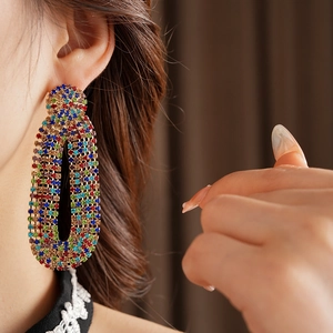 Close-up of vintage oval drop earrings with colorful rhinestones worn by a model