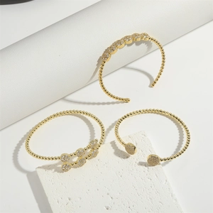 Detailed view of luxury gold-plated beaded bangles with pavé zircon stones on stone stand