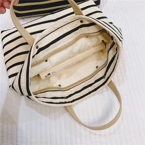 Detail view of striped canvas tote interior with zipper pocket and cream lining