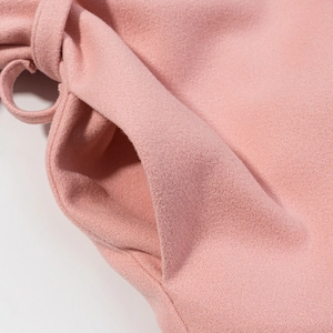 Dettaglio ravvicinato del cappotto di lana rosa con cuciture delle tasche e cintura