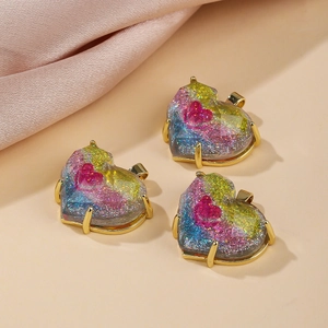 Close-up of heart-shaped glitter resin pendants with gold frames and pink inner hearts