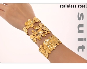 Close-up of golden floral patterned stainless steel cuff bracelet set on model's wrist