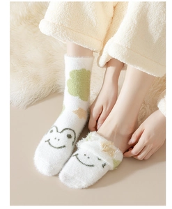 Close-up of cozy fuzzy frog socks with white, green and yellow cloud patterns on soft blanket