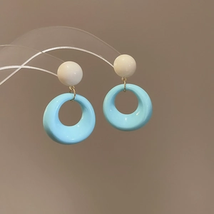 Macro shot of sky blue resin hoop earrings with cream stud and gold connectors
