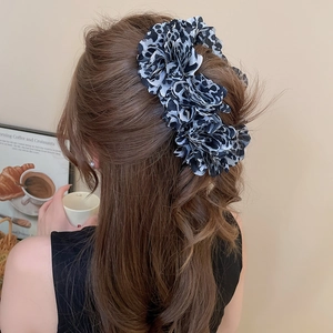 Detail of a large leopard print fabric flower hair clip worn for a half-up hairstyle